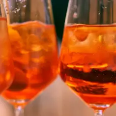 Trzy kieliszki z pomarańczowym drinkiem i lodem. Idealne do rozważań, jak dobrać rodzaj bittersa do klasycznego old fashioned.