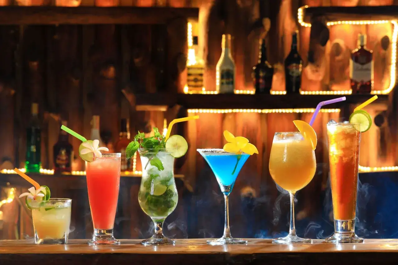 Kolorowe drinki na barze, idealne, by pokazać, jak przygotować autorski drink na powitanie gości na weselu.