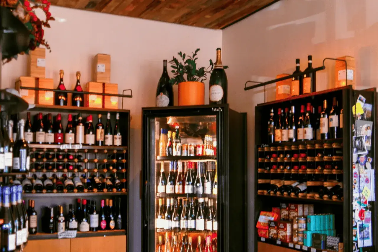 Wino w kuchni blisko piekarnika i światła może stracić swój smak. Na zdjęciu regały z butelkami wina, lodówka na wino i pudełka.