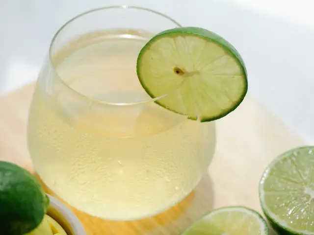 Szklanka orzeźwiającego napoju z plasterkiem limonki. Czy wiesz, jakie są przyczyny gorzkiego posmaku po wyciśnięciu limonki praską?