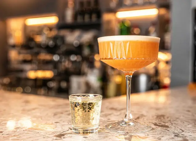 Domowe puree z marakui do Pornstar Martini. Koktajl w kieliszku coupe i shot z wódką na blacie barowym.
