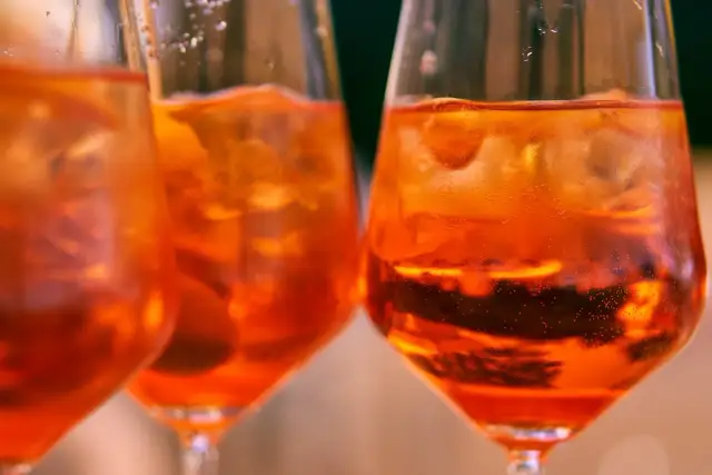 Trzy kieliszki z pomarańczowym drinkiem i lodem. Idealne do rozważań, jak dobrać rodzaj bittersa do klasycznego old fashioned.